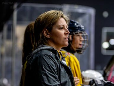 Woman coach intently watching an ice hockey game.
