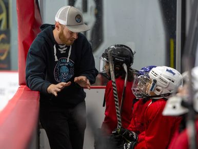 Coach giving instructions to young hockey players on the bench.