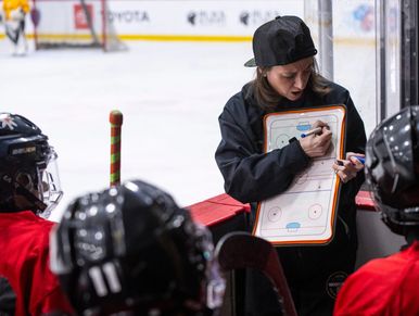 Coach instructing young hockey players during a game.