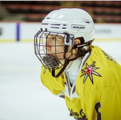 Young ice hockey player in yellow jersey focused on the game.