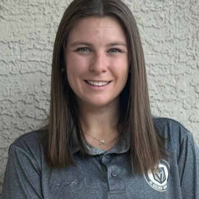 Young woman in a grey polo shirt smiling at the camera.
