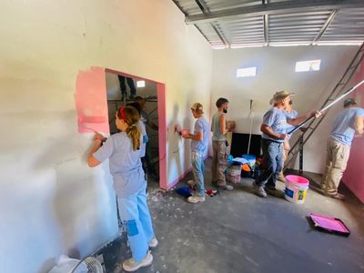 Group of people painting walls inside a building under renovation.
