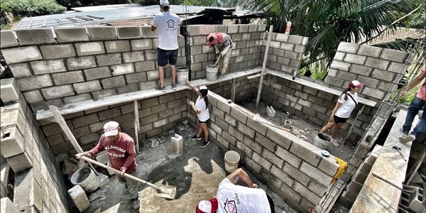 Workers building a brick structure with cement and tools.