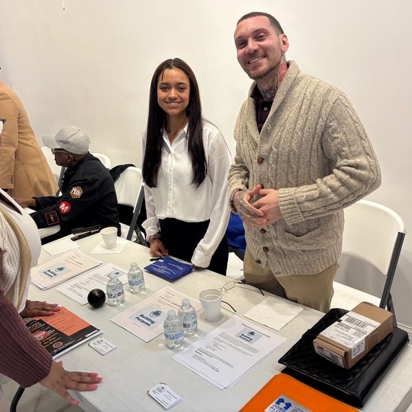 Two people smiling at a table with informational materials.