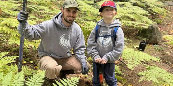 A man and a child hiking in a forest.