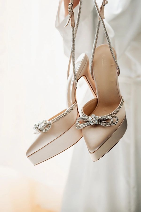 Elegant beige high-heeled shoes with rhinestone bows.