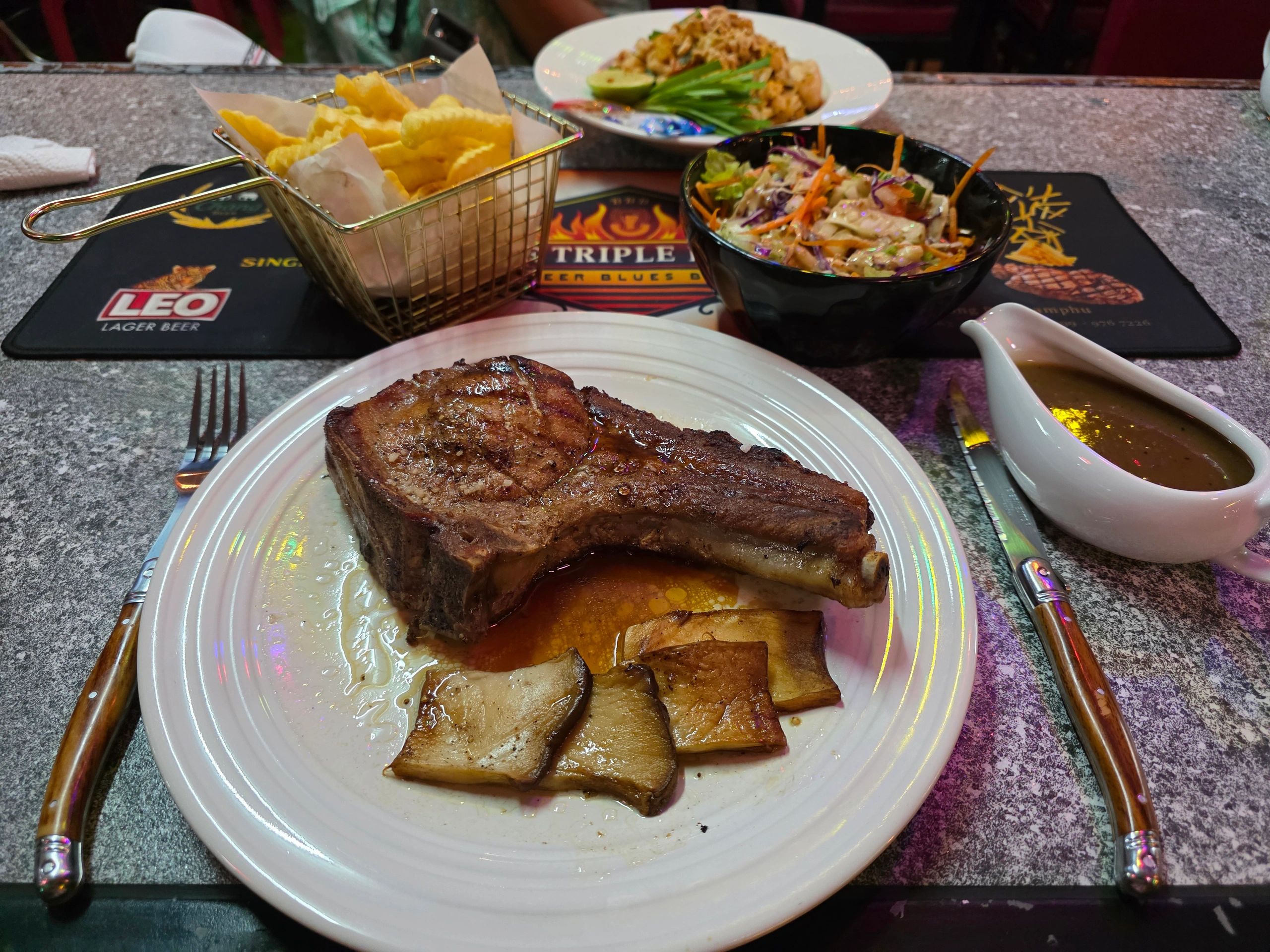 Steak with mushrooms, fries, salad, and sauce.