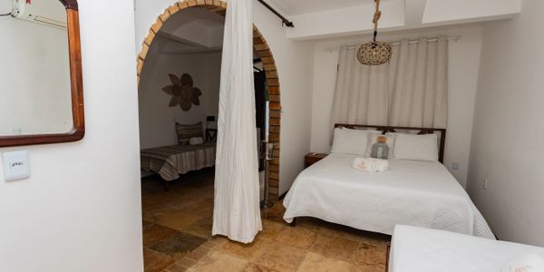 Cozy bedroom with white bedding and rustic stone flooring.