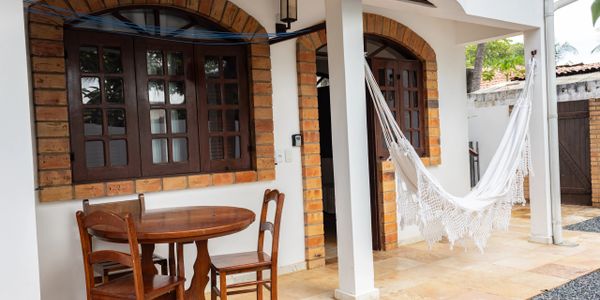 Cozy patio with wooden table, chairs, and a white hammock under arch windows.