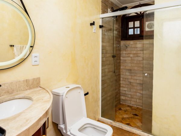 Bright bathroom with a glass shower enclosure and a toilet.