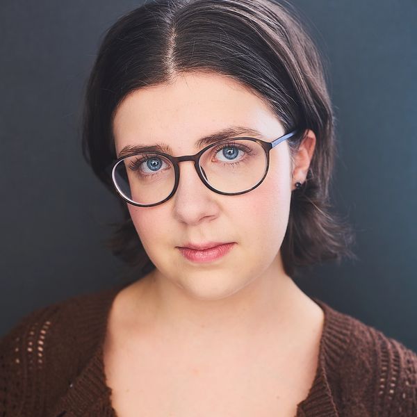 Close-up portrait of a woman with glasses and blue eyes.