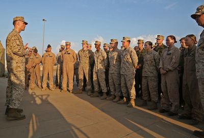 Military personnel standing in formation listening to a briefing.
