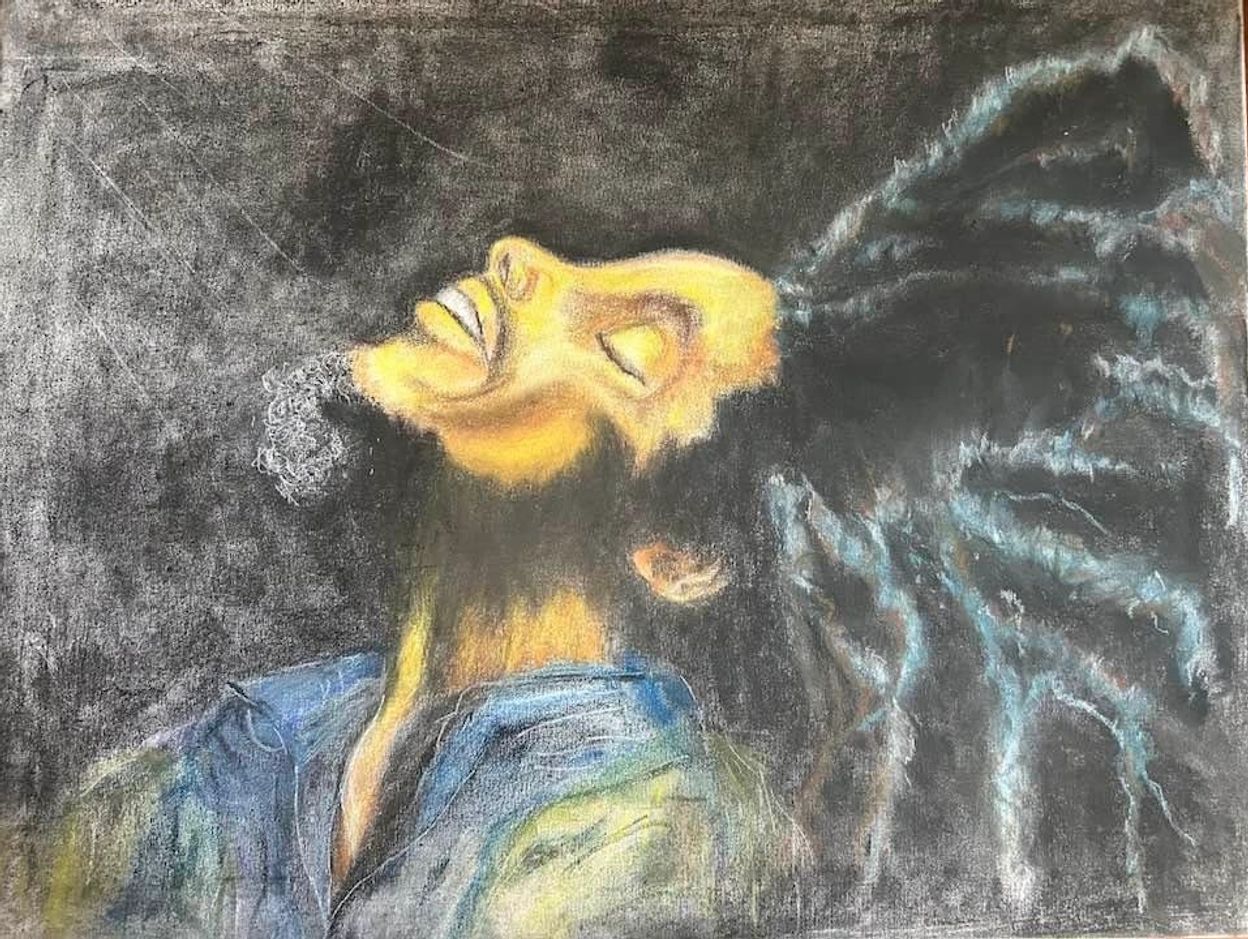 Artistic portrait of a man with dreadlocks smiling upward.