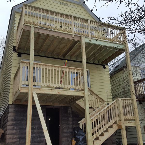 Newly constructed wooden balconies and stairs on a two-story house.