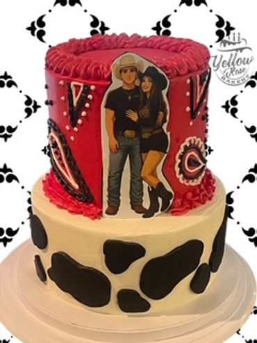 Two-tier cake with cowboy-themed decorations and a couple's image on top.