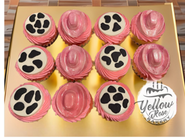 Pink cowboy hat and cow print cupcakes arranged on a gold tray.
