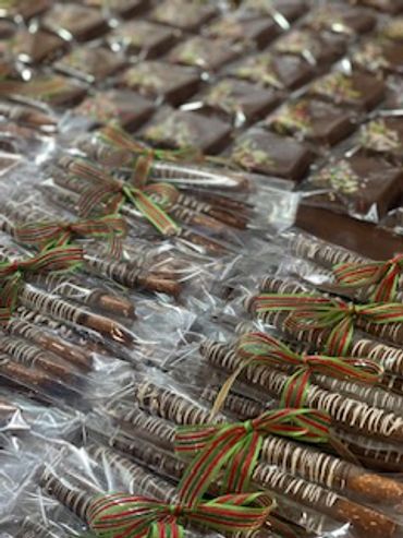 Rows of chocolate-covered pretzel sticks and squares with festive ribbons.