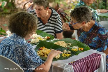 Group travelers from Europe savor Kannur's cuisine, enjoying local specialties.Kerala Tourism.