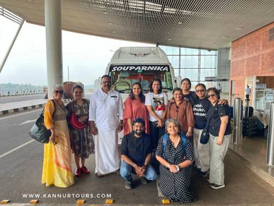Group of travelers posing in front of a tour bus at an airport.