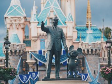 Statue of Walt Disney and Mickey Mouse at a castle.