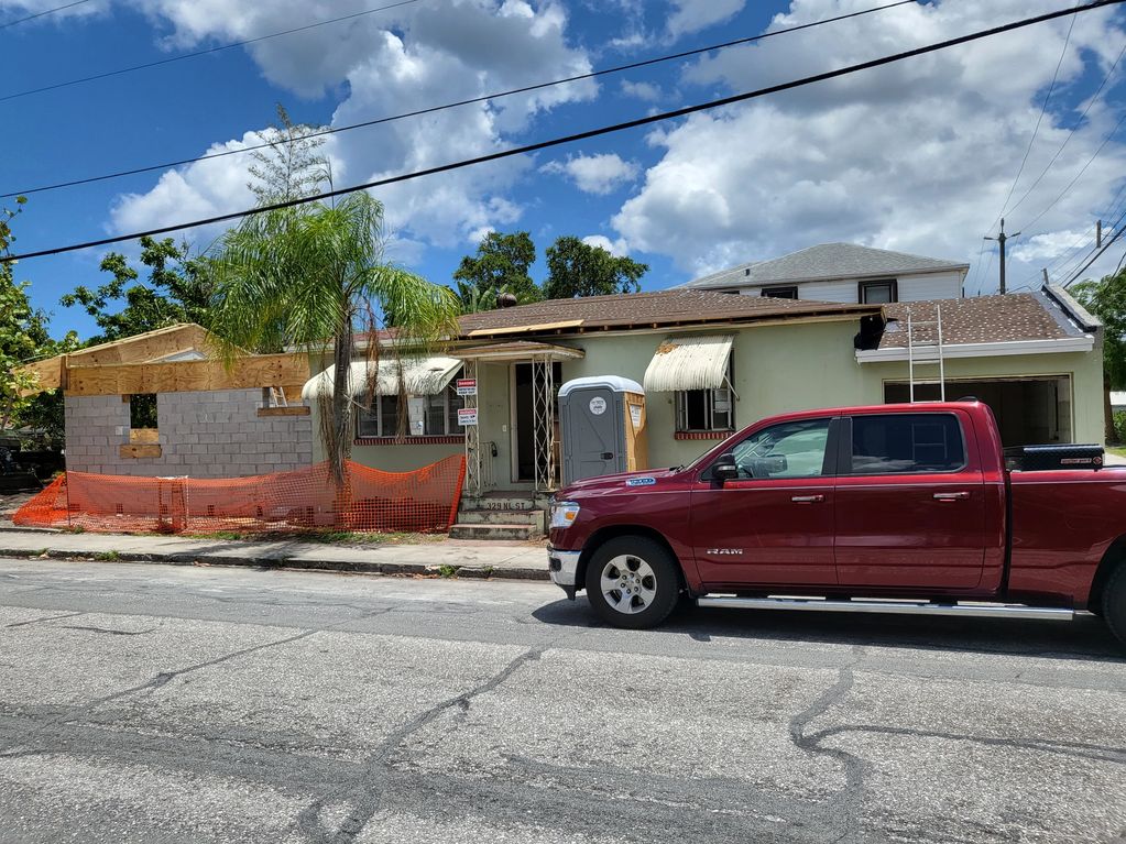 House under renovation with a red truck parked outside.