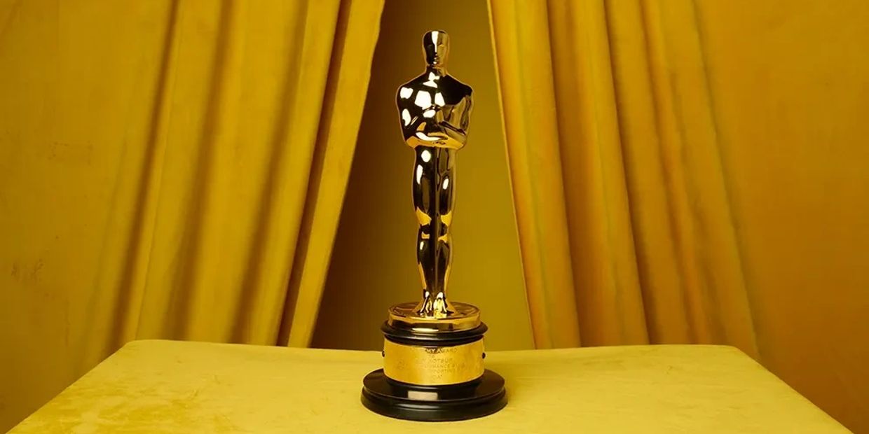 Golden Oscar statue on a yellow draped background.