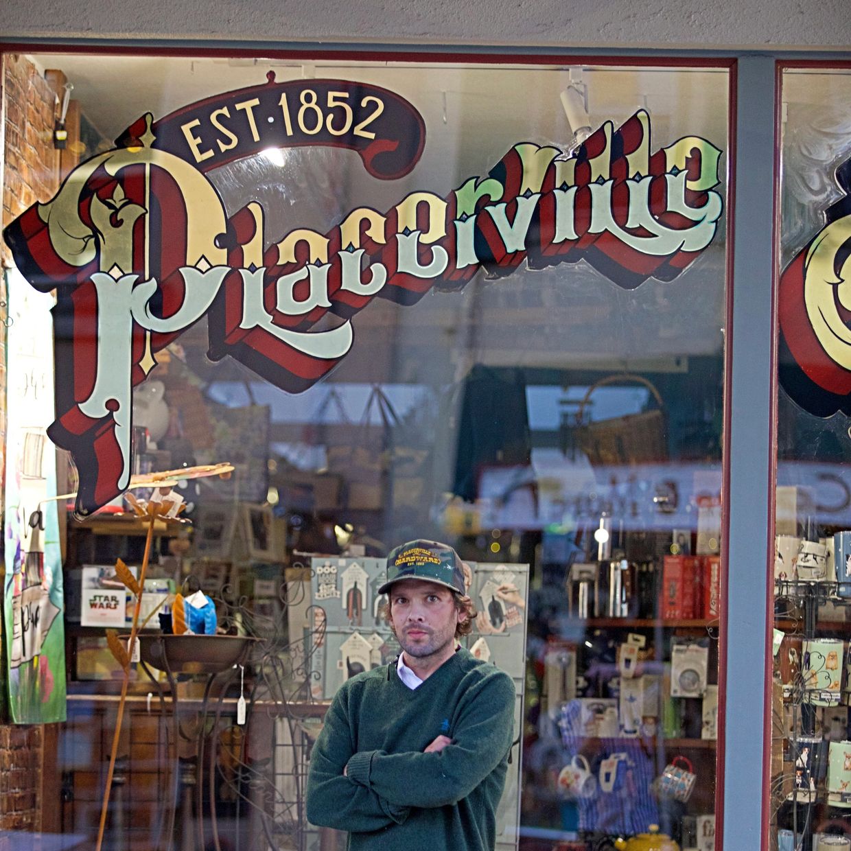 Man standing in front of a store window with 'Placerville' sign.