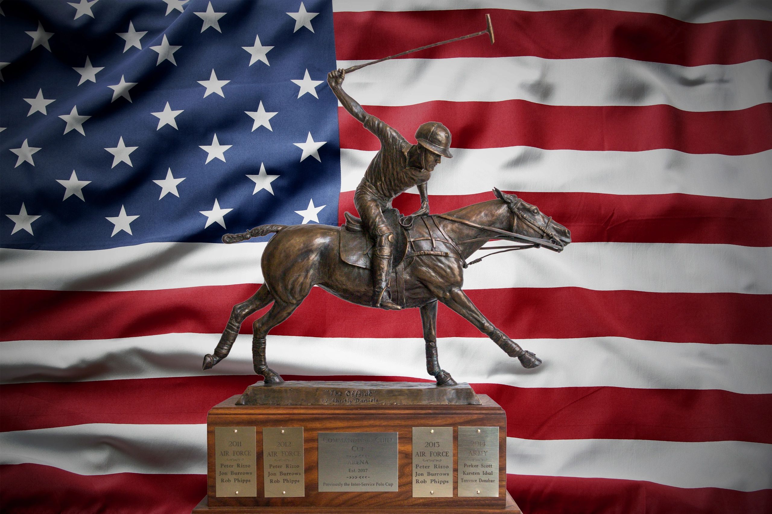 Bronze polo player statue on a trophy base with the American flag backdrop.