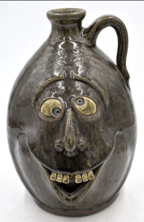 Ceramic jug with a comical, exaggerated human face design.