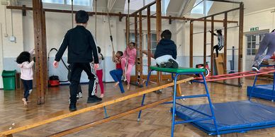 Children playing on gym equipment in a school gymnasium.