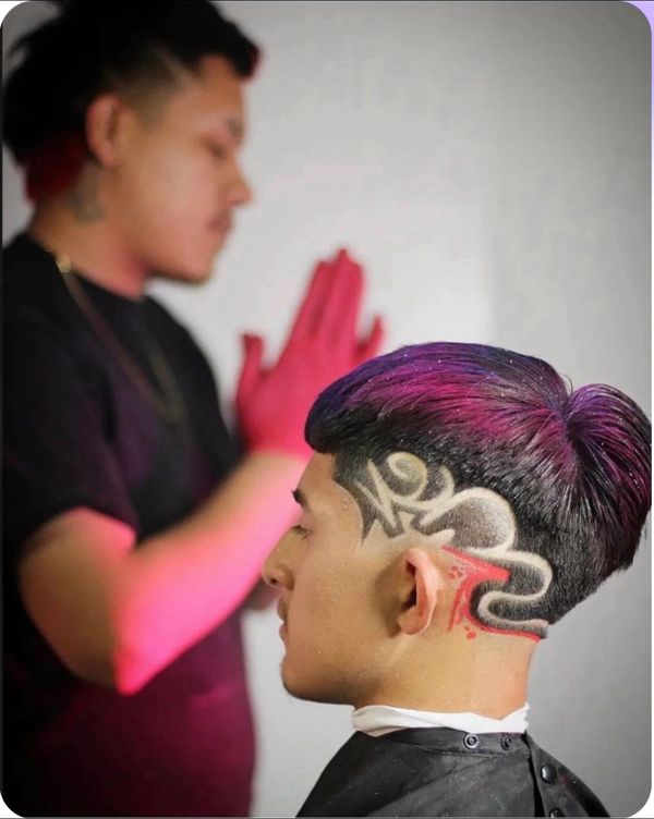 Man with a creative hair design featuring patterns and colored highlights.