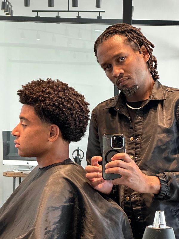 Barber taking a selfie with a client showing a fresh haircut.