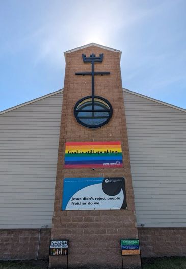 Church tower with banners promoting inclusivity and diversity.