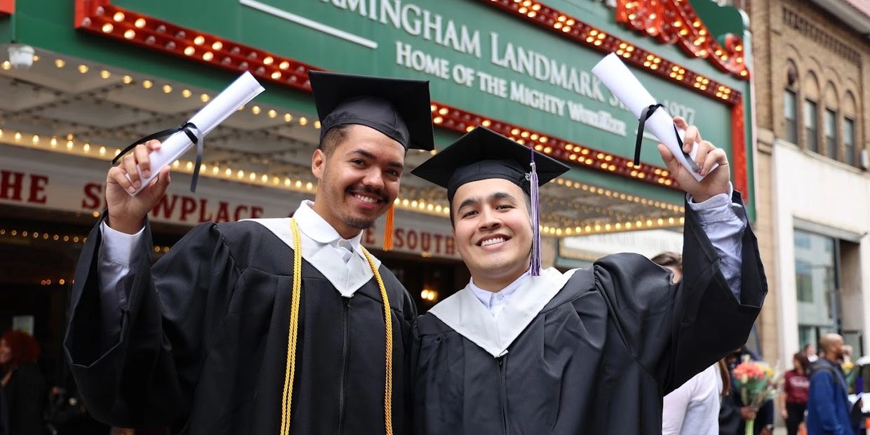 Two people holding up diplomas