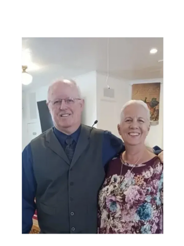 Smiling elderly couple posing together indoors, dressed nicely.