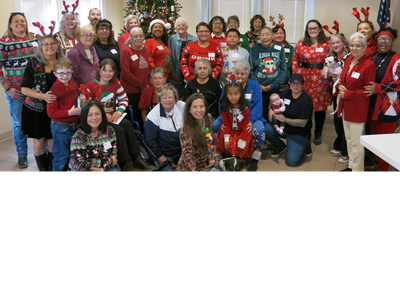 Group posing in holiday sweaters and reindeer antlers indoors.