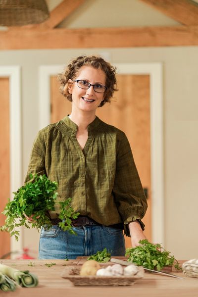 Gut Health Nutritionist smiling hold parsley in the kitchen