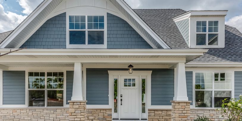 Blue and white house exterior with stone accents and large windows.