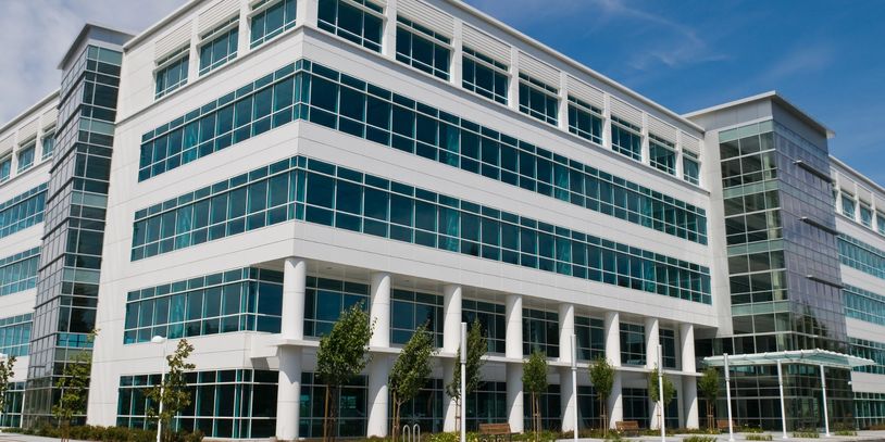 Modern office building with large glass windows under a clear sky.