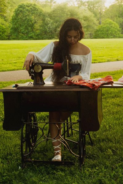 Young woman sewing outdoors on a vintage sewing machine.
