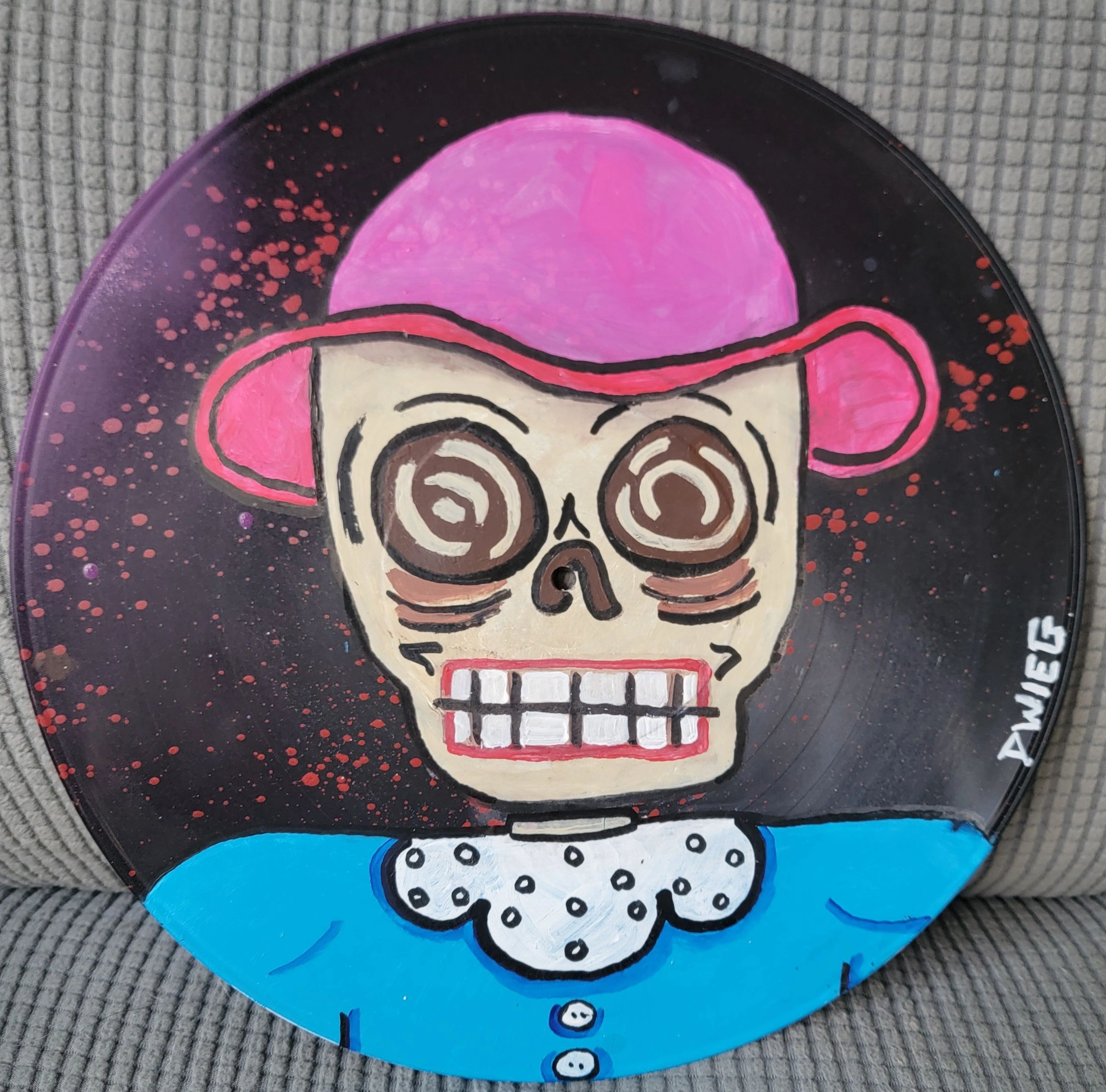 Painted vinyl record featuring a whimsical skull figure with pink hair and blue attire.