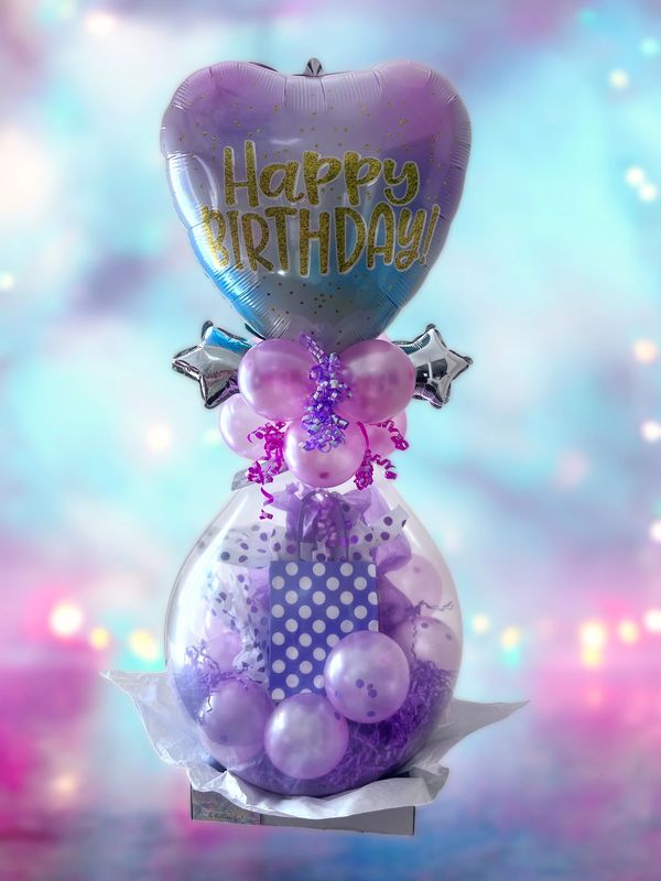 Purple-themed birthday balloon arrangement with gift bag and festive decorations.