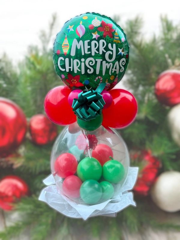 Festive Christmas balloon arrangement with green, red, and transparent balloons and a Merry Christmas message.