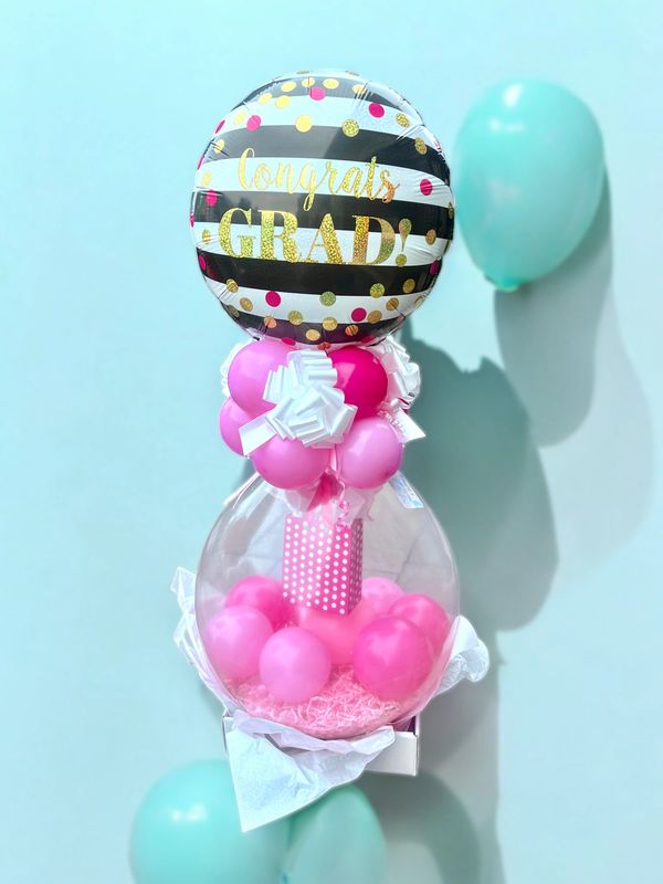 Colorful graduation balloon arrangement with pink and gold accents.