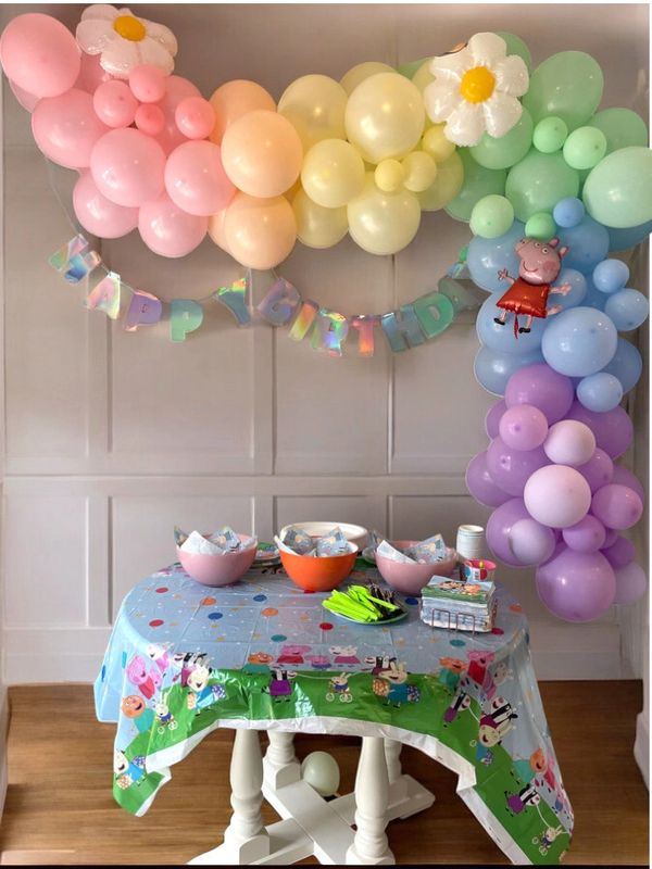 Colorful Peppa Pig-themed birthday party setup with balloons and decorations.