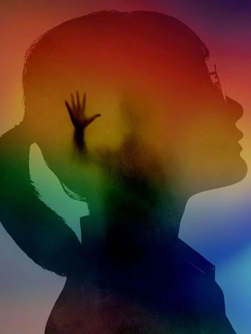 Silhouette of a woman with a raised hand inside her head against a colorful background.