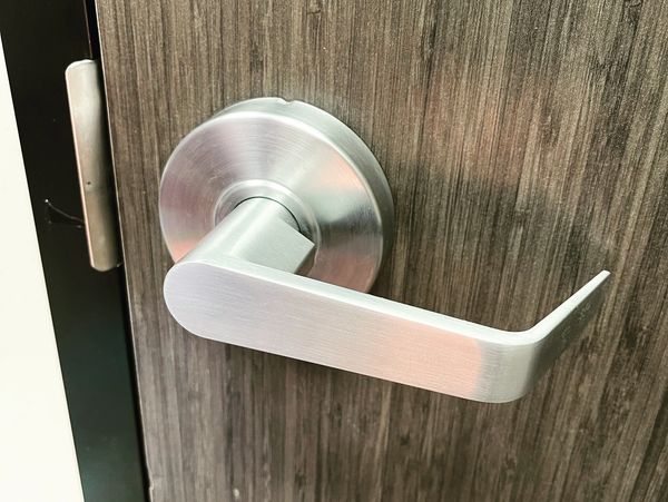 Commercial duty door lever. Stainless steel finish installed in wooden office door. 