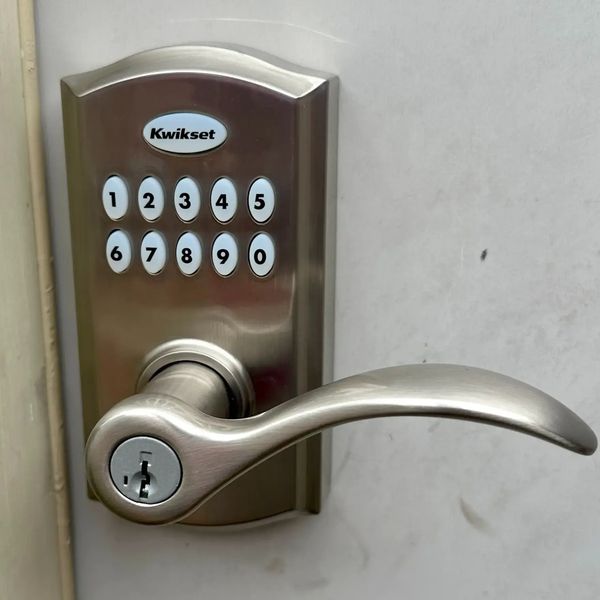 Kwikset digital door lock mounted on an exterior garage door in satin nickel finish