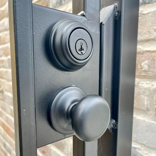 Black residential gate hardware. Deadbolt and door knob on black iron gate