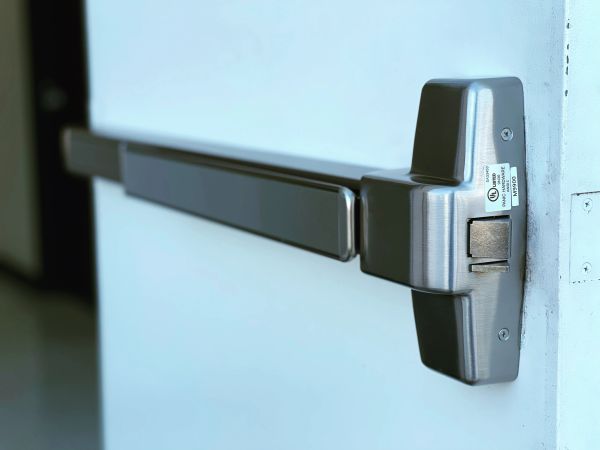 Close-up of a metal panic bar on a door.